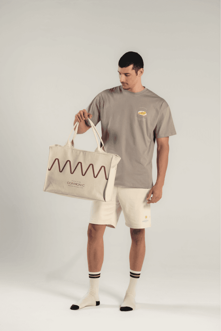 Model holding the cream Getaway tote with a burgundy wave, in cream socks